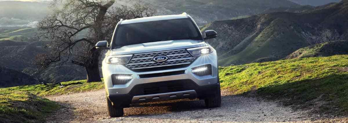 a grey suv driving on a gravel road in the mountains
