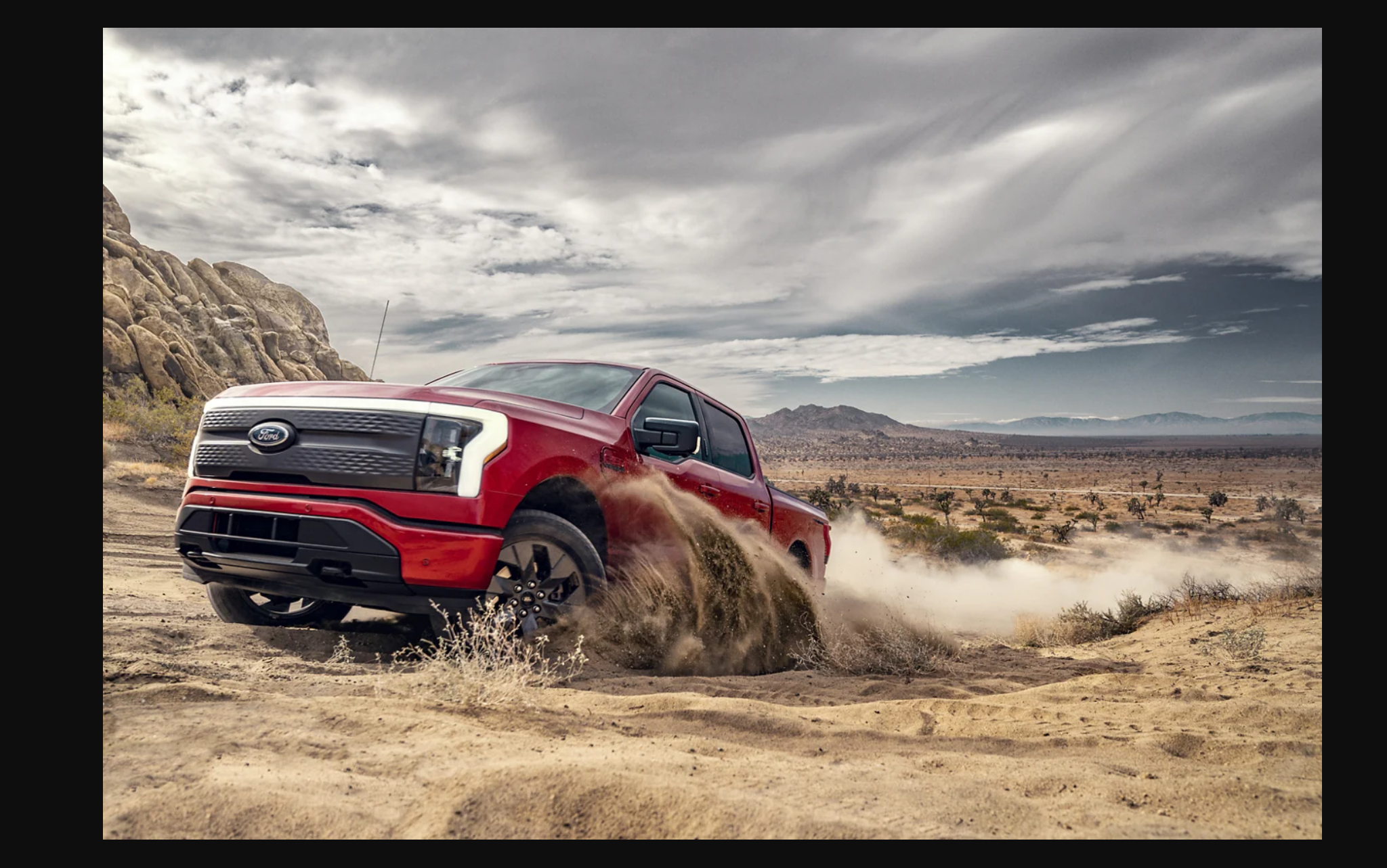 a red truck driving on a dirt road