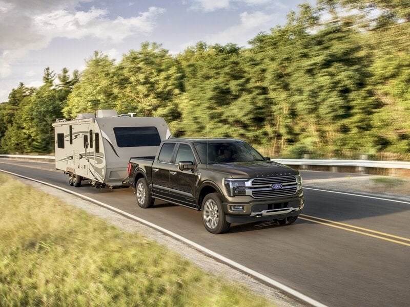 Ford F-150 truck hauling RV trailer home through scenic road with motion blur from Ford Dealer Near Catoosa, OK