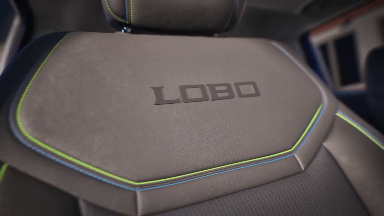 A detailed close-up of the Ford Maverick Lobo edition seat, featuring "LOBO" embroidered on the seatback with green and blue accent stitching.