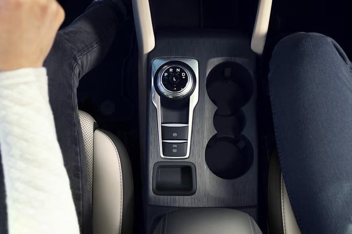 the driving consol of a vehicle showing cupholders