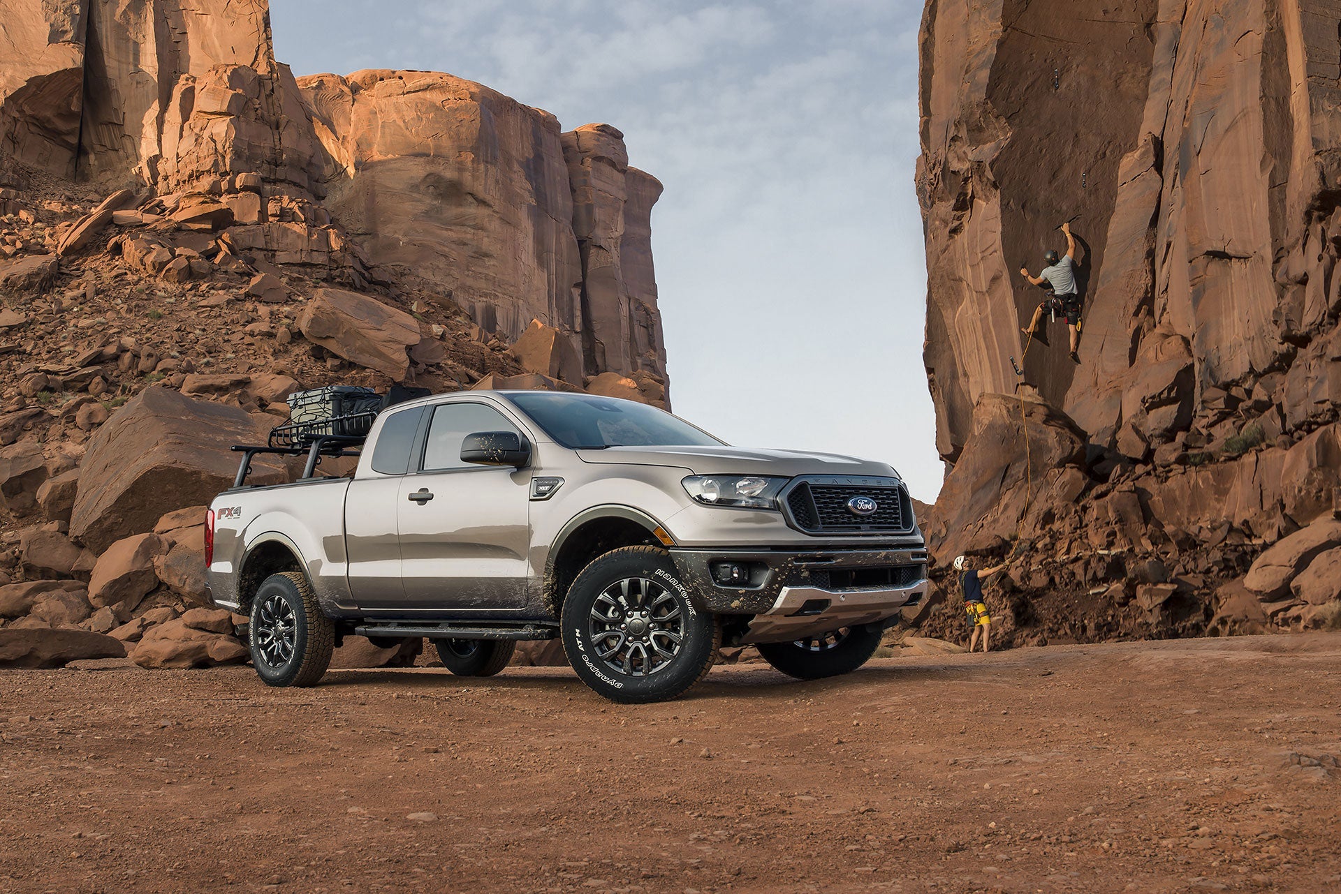 a tan truck parked in the desert with boulders in the background