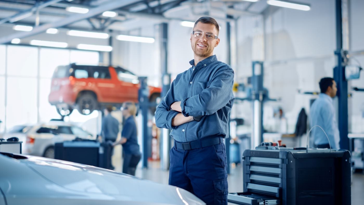 Ford Certified Technician smiling at camera while standing in middle of Ford Service Center near Catoosa OK