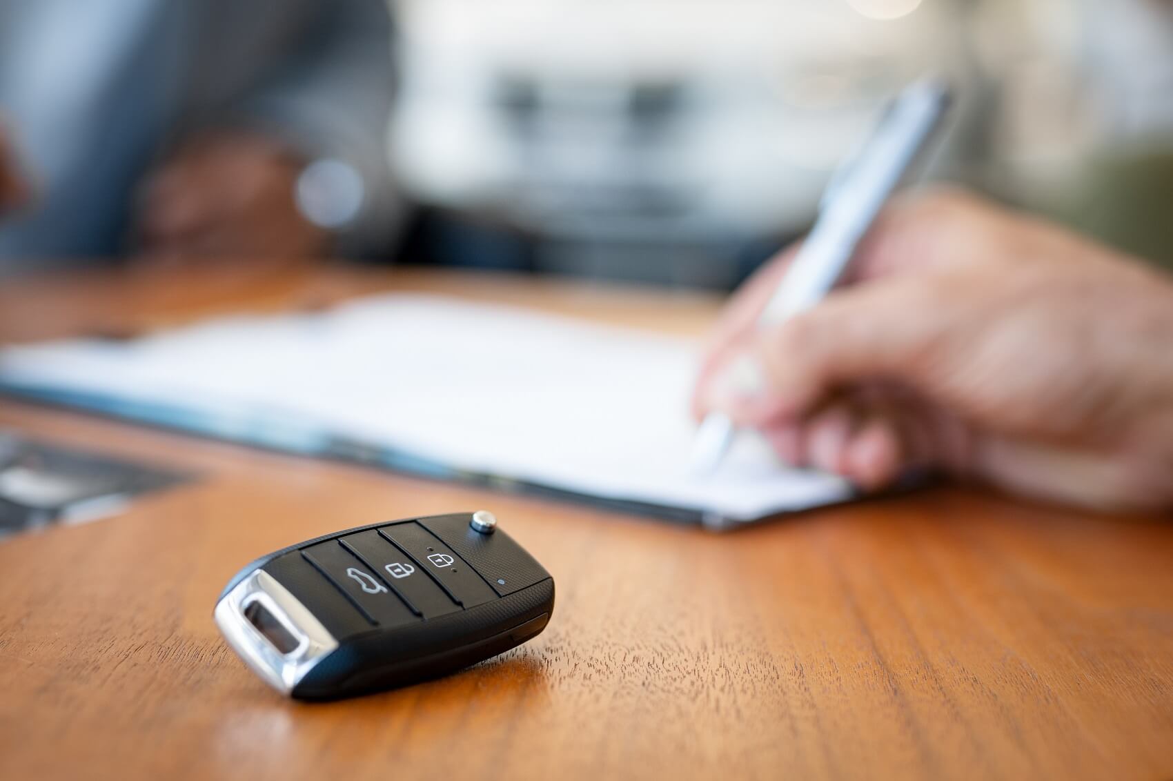 Ford customer signing finance papers with key fob in the foreground
