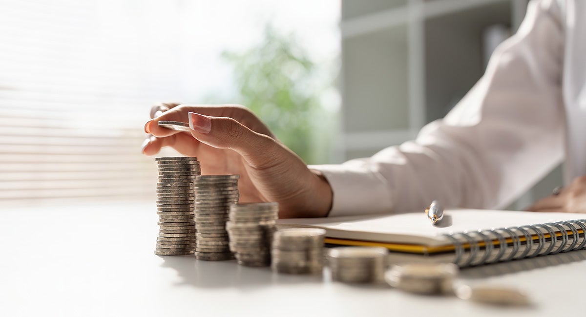 a person counting quarters in a row with a notebook and pen