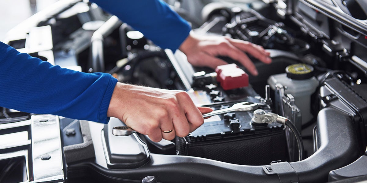 a ford service technician working under the hood of a vehicle